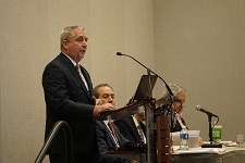 Male dressed in a suit speaking from a podium.