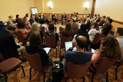 Photo of what appears to be a breakout session with people sitting in chairs that are arranged in a large circle.