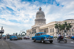 Photo of the Cuban capitol building with classic cars visible on the street.