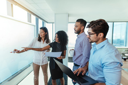 Four professionals standing and working together before a white baord.