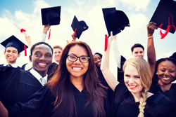 Diverse group of students smiling in celebration as they all wear their graduation caps and gowns. 