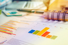 Desk covered in scattered papers with various bar graphs visible. 