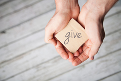 Cupped hands holding a cardboard square that says "give."