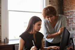 Two females work together over a computer.