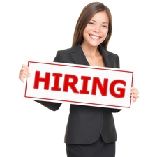 Female in a business suit holding a sign that says "hiring" in red ink. 