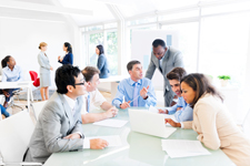 White room with business professionals interacting in various groups.