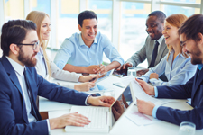 Group of professionals smiling and conversing while sitting around a table.