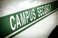 Photo of the side of a white car with the words "campus security" bordered by a green banner.