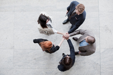 Five people standing in a circle with their hands stacked in the center as though they're about to break.