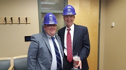 Photo of LeRoy Rooker with an unknown male. Both men are wearing blue construction hats and smiling.