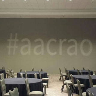 Photo of an empty event space with "#aacrao" projected on a plain wall.