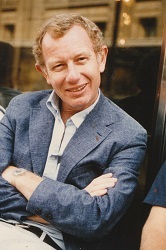 Photo of an unidentified man sitting down with his arms crossed.