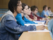 College students taking notes while listening to a lecture.