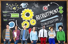 Group of people standing together in front of a giant blackboard with various symbols and words written in chalk on it. 