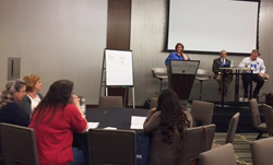 Photo of what appears to be a breakout session with some audience members sitting at circular table.